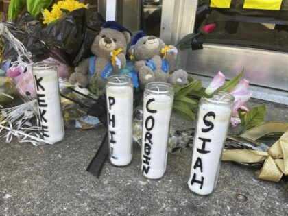 Candles with the names of the four young people killed in a shooting and teddy bears dress