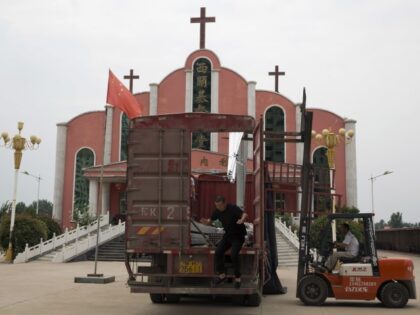 In this photo taken Saturday, June 2, 2018, a worker jumps from a truck parked in front of a church and the Chinese national flag near the city of Pingdingshan in central China's Henan province. Under President Xi Jinping, China's most powerful leader since Mao Zedong, believers are seeing their …