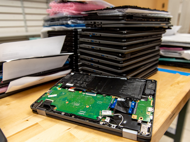 A stack of broken Chromebook laptops at Cell Mechanic Inc. electronics repair shop in West
