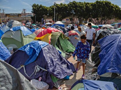 17 March 2021, Mexico, Tijuana: A child walks through tents at a migrant camp on the groun