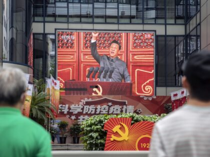 Pedestrians watch a screen showing a live news broadcast of Chinese President Xi Jinping speaking at a ceremony marking the centenary of the Chinese Community Party, taking place at Beijing's Tiananmen Square, in Shanghai, China, on Thursday, July 1, 2021. President Xi Jinping is set to deliver a speech linking …