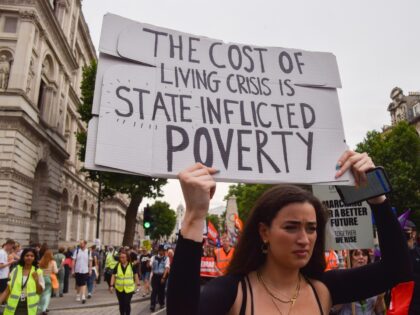 LONDON, UNITED KINGDOM - 2022/06/18: A protester holds a placard calling the cost of living crisis "state-inflicted poverty", during the demonstration in Whitehall. Thousands of people and various trade unions and groups marched through central London in protest against the cost of living crisis, the Tory Government, the Rwanda refugee …