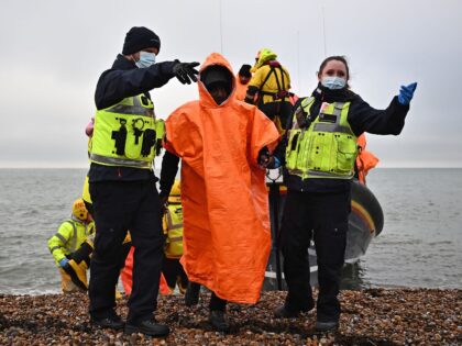 A British Immigration Enforcement officers escort migrants, picked up at sea by an Royal National Lifeboat Institution (RNLI) lifeboat whilst they were attempting to cross the English Channel, on the shore at Dungeness on the southeast coast of England, on December 9, 2022. (Photo by Ben Stansall / AFP) (Photo …