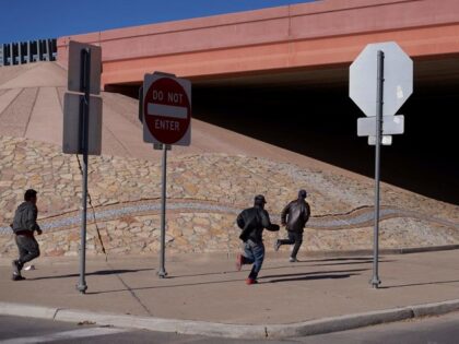 TOPSHOT - Migrants run into the street to evade law enforcement after illegally crossing into the US via a hole in a fence in El Paso, Texas, on December 22, 2022. - The US Supreme Court halted December 19, 2022 the imminent scrapping of a key policy used since Donald …