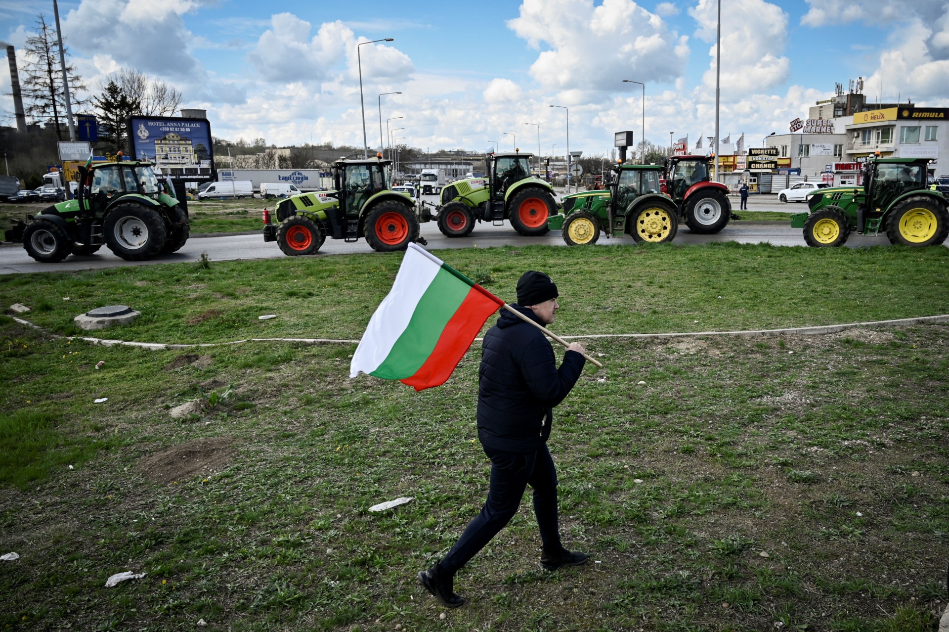 A farmer waves the Bulgarian flag during an action to block trucks crossing the Danube bridge, marking the border between Bulgaria and Romania in a protest against the duty-free import of grain coming from Ukraine into the EU, in Rousse on March 29, 2023. (Photo by Nikolay DOYCHINOV / AFP) (Photo by NIKOLAY DOYCHINOV/AFP via Getty Images)