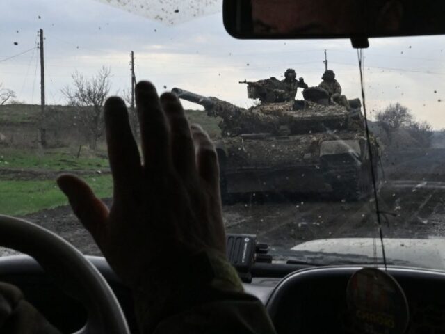 Ukrainian servicemen greets each other as they drive along a road near the town of Bakhmut