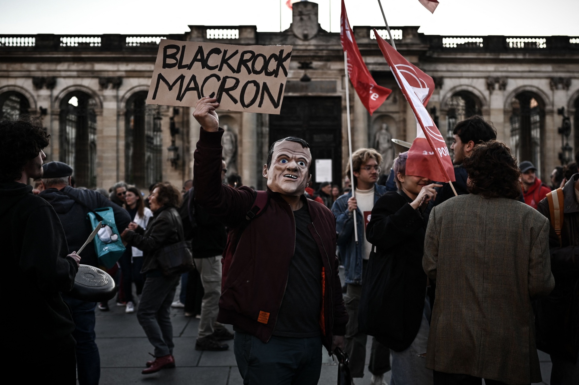 A demonstrator wearing a mask of French President Emmanuel Macron, takes part in a concert of pans to protest during president's televised address to the nation, after signing into law a pensions reform, in front of the city hall in Bordeaux, southwestern France, on April 17, 2023. (Photo by Philippe LOPEZ / AFP) (Photo by PHILIPPE LOPEZ/AFP via Getty Images)