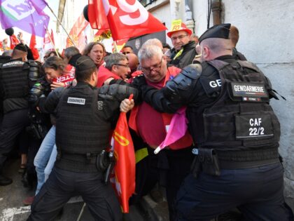 Protesters try to push past French Gendarme towards a collage, as they wait for the arrival of the French President a month after his government pushed an unpopular pensions reform act through parliament, in Ganges, southern France on April 20, 2023. - The 45-year-old French President has been encouraged by …