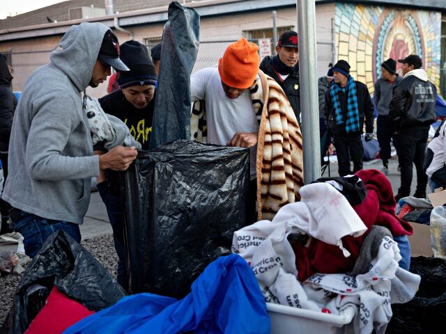 EL PASO, TEXAS - JANUARY 08: Immigrants receive donated clothing outside a migrant shelter on January 08, 2023 in El Paso, Texas. President Joe Biden is set to visit El Paso Sunday, his first visit to the border since he became president two years ago. U.S. Border authorities took into …