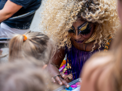Drag Queen Beatrice Thomas, also known as Black Benatar, face paints children during a sto