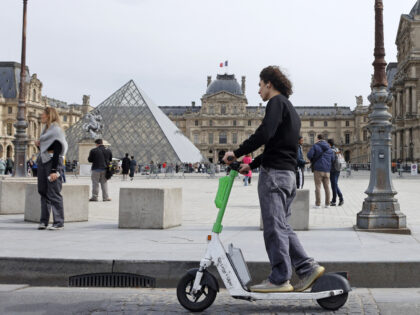 PARIS, FRANCE - MARCH 29: A man rides a Lime electric scooter in front of the Louvre pyramid and the Louvre museum on March 29, 2023 in Paris, France. The Mayor of Paris, Anne Hidalgo is organizing a local referendum on Sunday April 2, 2023 to ask Parisians if they …