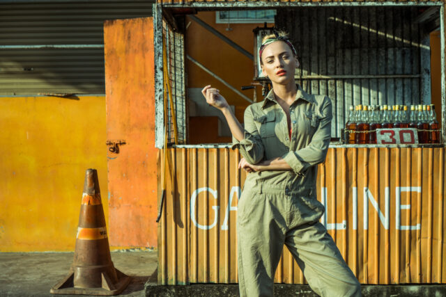 Sensual blond woman in orange bra, light brown coverall and bandana looking at the camera