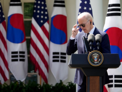 President Joe Biden takes his sunglasses of at a news conference with South Korea's P