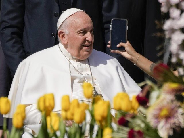 A woman holds a phone as Pope Francis leaves after his weekly general audience in St. Pete