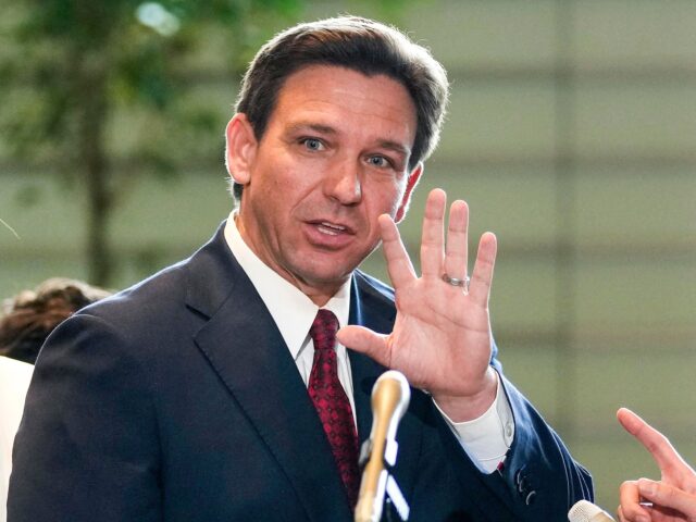 Florida Governor Ron DeSantis (R) waves to journalists as his wife Casey (L) looks one aft