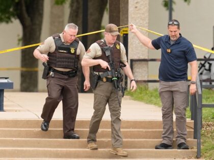 Oklahoma state troopers walk under police tape following a fatal shooting at Rose State Co