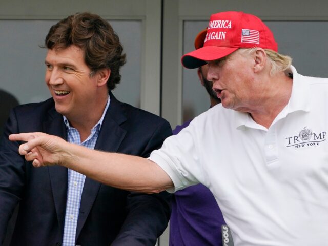 Tucker Carlson, left, and former President Donald Trump, talk while watching golfers on th