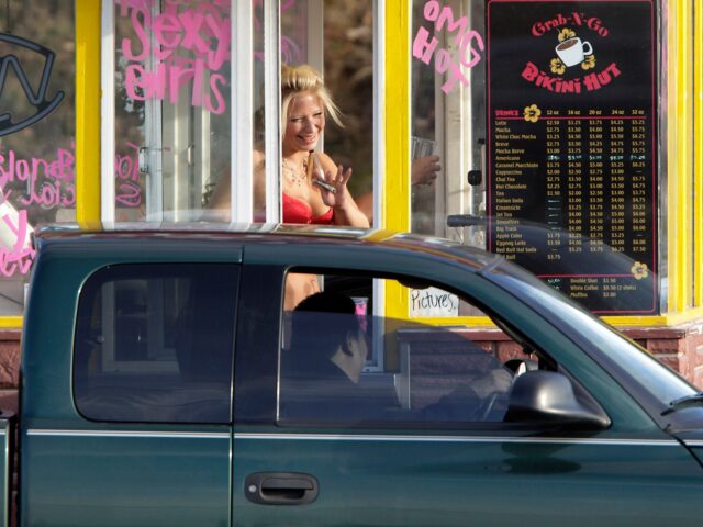 A barista at a Grab-N-Go Bikini Hut espresso stand holds money as she waves to a customer,