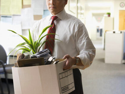 Fired businessman carrying box of personal items - stock photo