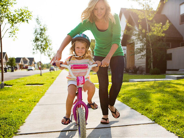 Mother teaching her daughter how to ride a bicycle.