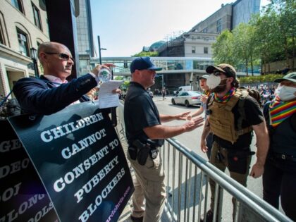 Police stand between anti-trans activist Chris Elston (L) and counterprotestors (R) as they confront each other outside of Boston Childrens Hospital in Boston, Massachusetts, on September 18, 2022. - Protestors for and against the hospital's programs that deal with gender affirmation surgeries and hormonal treatments were gathered outside the hospital. …
