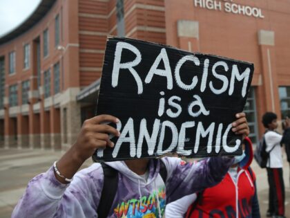 Quincy - November 12: A person holds a sign that reads racism is a pandemic as dozens of Quincy High School students walked out on Nov. 12, 2021, protesting the administrations response to a racist video created by a student, which triggered that a fight with another student this week …