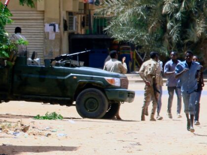 People run past a military vehicle in Khartoum on April 15, 2023, amid reported clashes in the city. - Sudan's paramilitaries said they were in control of several key sites following fighting with the regular army on April 15, including the presidential palace in central Khartoum. (Photo by AFP) (Photo …
