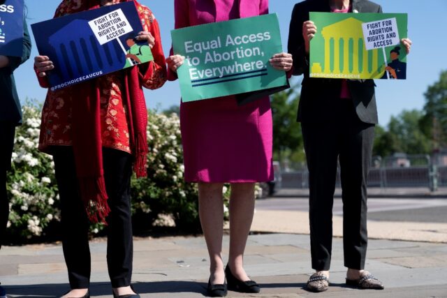 US members of Congress hold signs calling for equal abortion access on Capitol Hill in Was