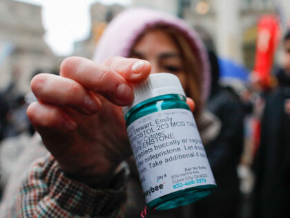 A pro-abortion activist displays abortion pills as she counter-protests during an anti-abo