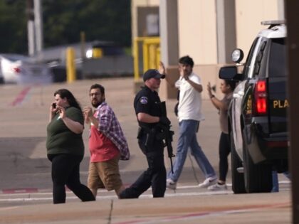 CORRECTS DATELINE TO ALLEN, TEXAS, INSTEAD OF FRISCO, TEXAS - People raise their hands as they leave a shopping center following reports of a shooting, Saturday, May 6, 2023, in Allen, Texas. (AP Photo/LM Otero)