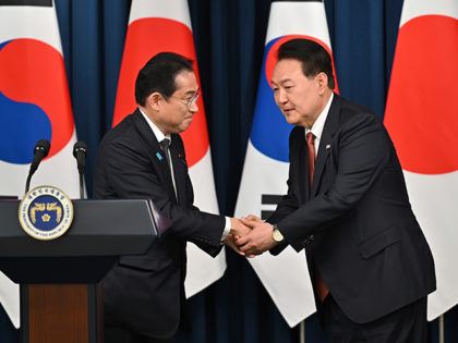 South Korean President Yoon Suk Yeol, right, shakes hands with Japanese Prime Minister Fum