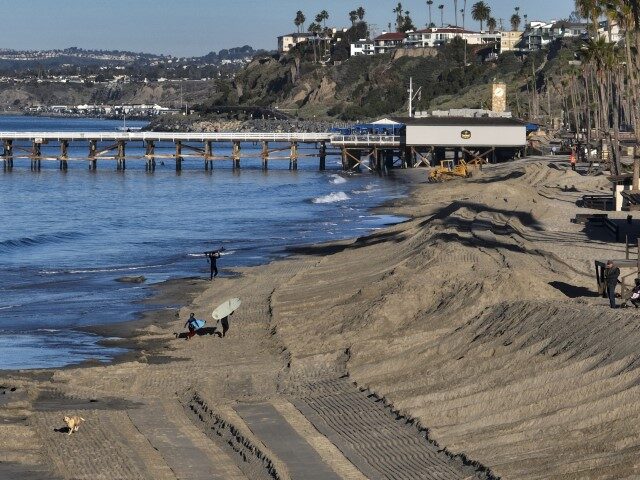 Workers use a tractor to build a sand berm south of the pier in San Clemente, CA, on Wedne