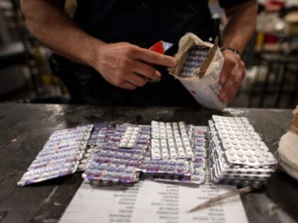 An officer from the US Customs and Border Protection, Trade and Cargo Division finds Oxycodone pills in a parcel at John F. Kennedy Airport's US Postal Service facility on June 24, 2019 in New York. - In a windowless hangar at New York's JFK airport, dozens of law enforcement officers …