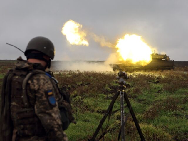 TOPSHOT - A Ukrainian soldier stands as a 2S1 Gvozdika self-propelled howitzer fires a she
