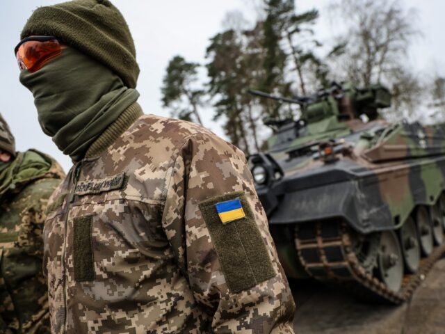 An Ukrainian soldier translator attends a press statement in front of an infantry fighting