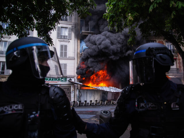 PARIS, FRANCE - MAY 1: French riot poilce surrounding a building on fire during a protest