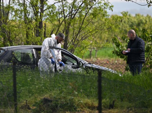 A forensic investigator works at one of the crime scenes, outside of the village of Dubona
