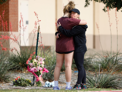MacKenzie Bates (L), 17, of Allen, Texas, embraces her mother Rochelle where flowers were left at the scene of a shooting the day before at Allen Premium Outlets on May 7, 2023 in Allen, Texas. According to reports, a shooter opened fire at the outlet mall, killing eight people. The …