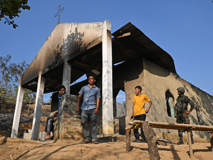 An Indian army soldier (R) stands along with villagers in front of a ransacked church that