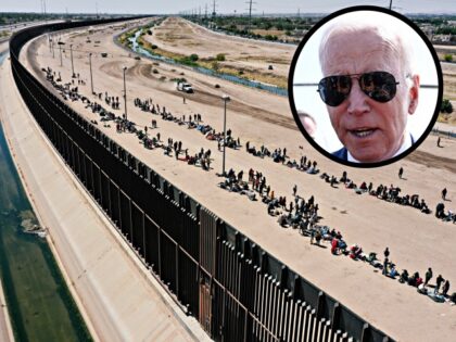 An aerial image shows migrants waiting along the border wall to surrender to US Customs an