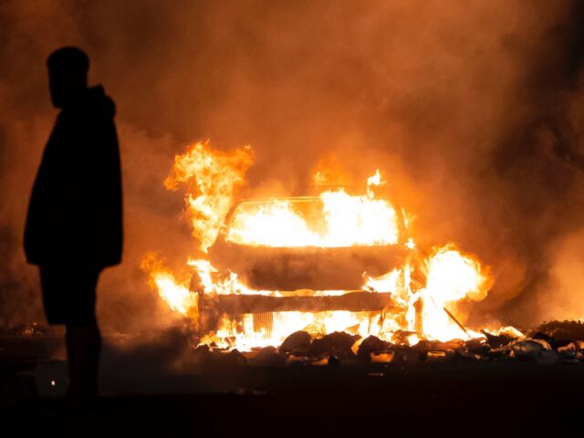 CARDIFF, WALES - MAY 23: An automobile burns on Highmead Road during unrest following a se