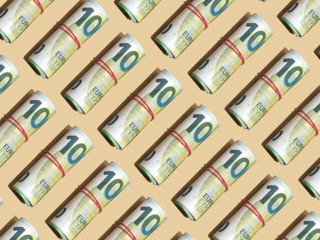 Roll of 100 euro banknotes on the beige background