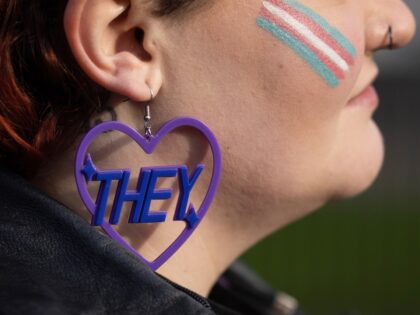 LONDON, ENGLAND - JANUARY 17: A Trans rights activist wears an earring featuring a 'they' pronoun symbol, during a protest outside the Ministry of Defence Main Building in Whitehall on January 17, 2023 in London, England. Rishi Sunak announced yesterday that the UK government will use a Section 35 order …