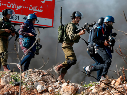An Israeli soldier pushes away journalists during clashes with Palestinian youths in the village of Silwad, in the Israeli occupied West Bank, on December 11, 2015, following a demonstration calling for the return of the bodies of alleged Palestinian attackers. Since October 1, almost daily attacks on Israelis and clashes …