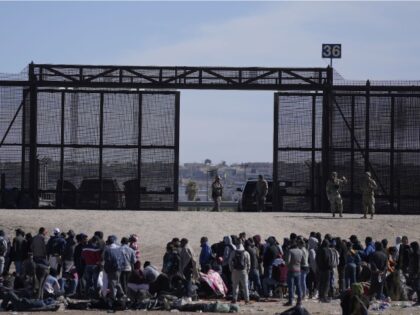 FILE - Migrants who crossed the border from Mexico into the U.S. wait next to the U.S. border wall where U.S. Border Patrol agents stand guard, seen from Ciudad Juarez, Mexico, Thursday, March 30, 2023. The Biden administration will open migration centers in South and Central America for asylum seekers …