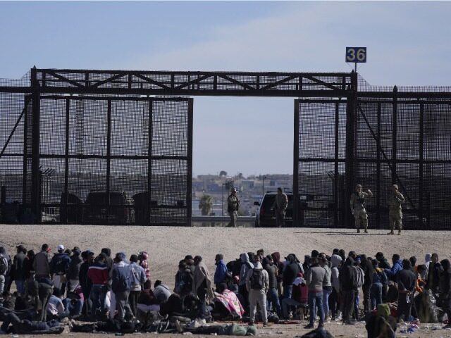 FILE - Migrants who crossed the border from Mexico into the U.S. wait next to the U.S. bor
