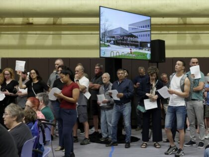 Attendees listen to speakers during an information and discussion meeting about housing mi