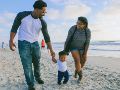 A couple and a baby walk on a beach (Pexels/Lawrence Crayton).