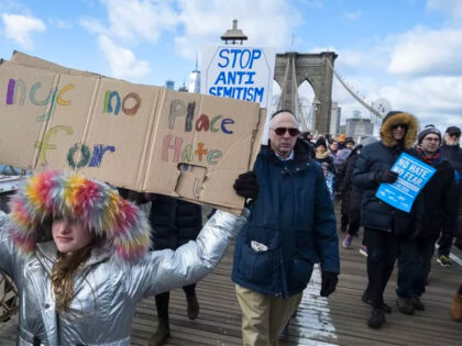MANHATTAN, NY - JANUARY 05: A Marcher hold signs that reads "NYC No Place for Hater" and another behind them "Stop Anti-Semitism" as they walk across the Brooklyn Bridge with the arch behind them. This was part of the effort to support the No Hate No Fear Solidarity March which …