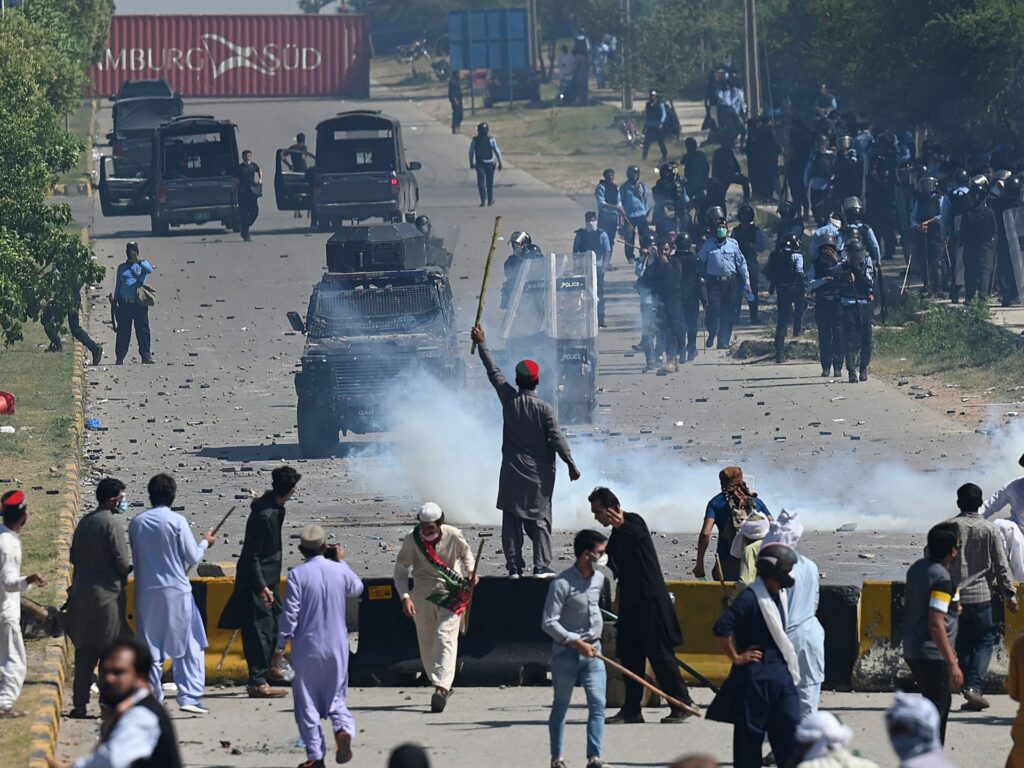 Police (back) use teargas to disperse Pakistan Tehreek-e-Insaf (PTI) party activists and supporters (foreground) of former Pakistan's Prime Minister Imran Khan during a protest against the arrest of their leader, in Islamabad on May 10, 2023. Khan will appear in a special court at the capital's police headquarters to answer graft charges on May 10, a day after his shock arrest prompted violent nationwide protests. (Photo by Aamir QURESHI / AFP) (Photo by AAMIR QURESHI/AFP via Getty Images)